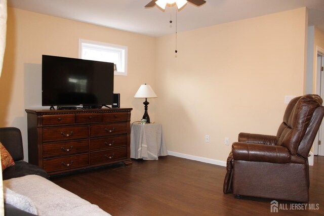 living area with ceiling fan and dark wood-type flooring