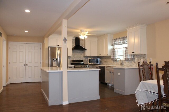 kitchen with wall chimney exhaust hood, stainless steel appliances, white cabinets, and a kitchen island