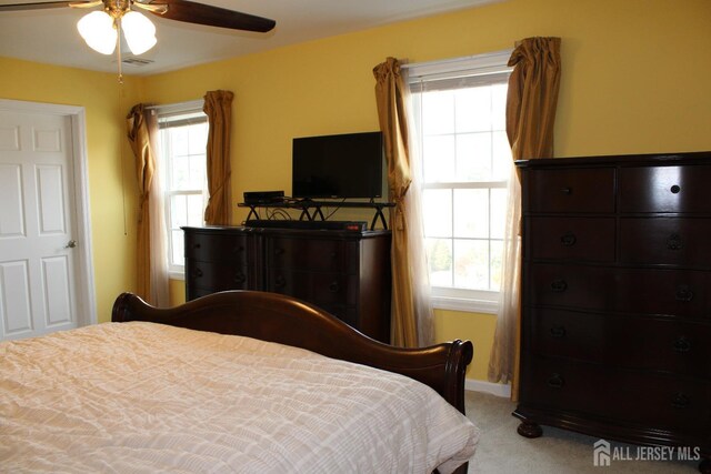 carpeted bedroom featuring multiple windows and ceiling fan