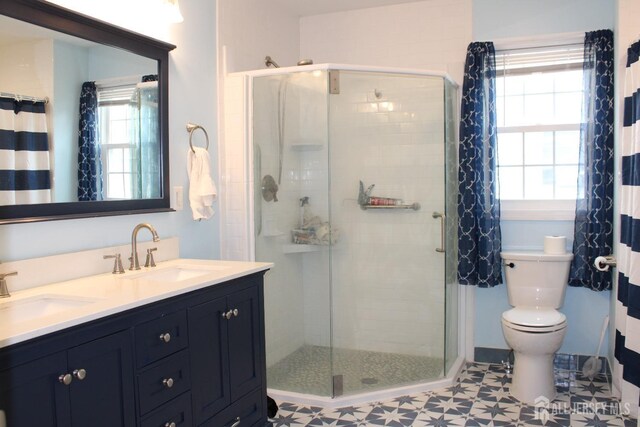 bathroom with toilet, tile patterned flooring, tiled shower, and vanity