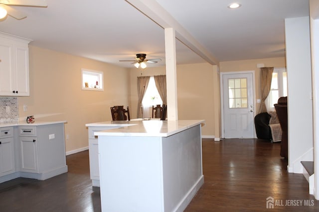 kitchen featuring dark hardwood / wood-style flooring, white cabinetry, ceiling fan, and backsplash