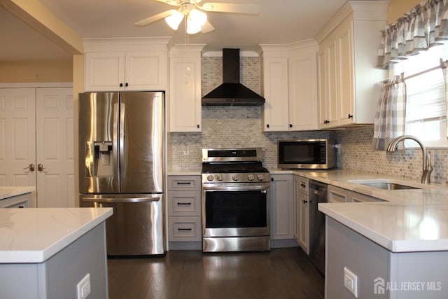 kitchen with wall chimney exhaust hood, decorative backsplash, white cabinets, appliances with stainless steel finishes, and sink