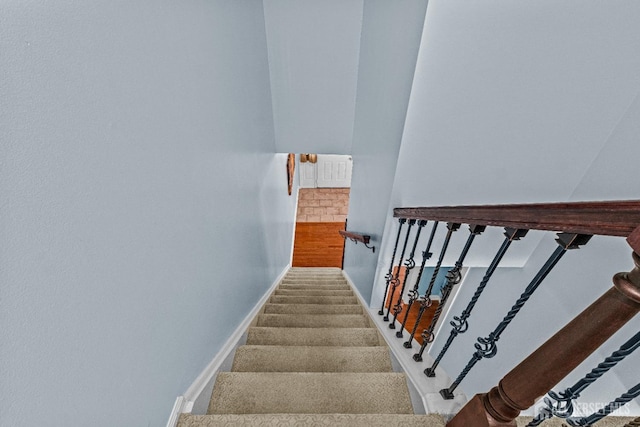 stairway featuring baseboards and carpet floors