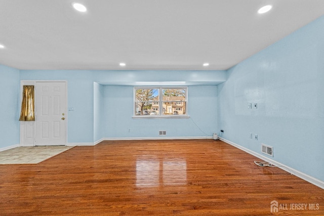 unfurnished living room featuring recessed lighting, wood finished floors, visible vents, and baseboards