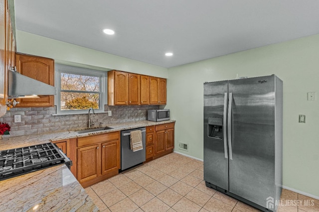 kitchen featuring brown cabinetry, decorative backsplash, appliances with stainless steel finishes, and a sink