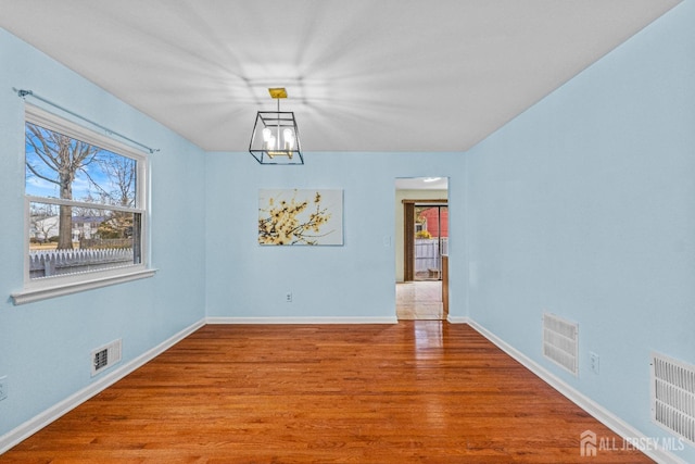 unfurnished dining area with visible vents, baseboards, and wood finished floors