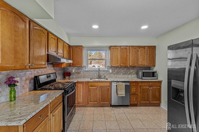 kitchen featuring under cabinet range hood, stainless steel appliances, brown cabinets, and a sink