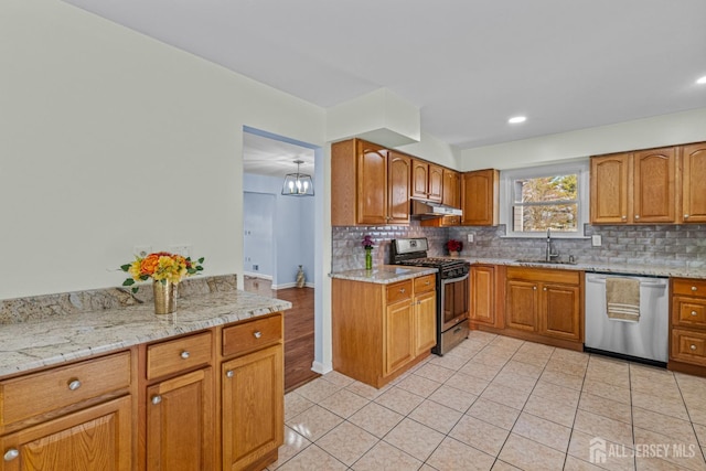 kitchen with under cabinet range hood, stainless steel appliances, decorative backsplash, and a sink