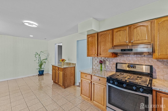 kitchen with stainless steel range with gas cooktop, under cabinet range hood, light stone counters, decorative backsplash, and light tile patterned floors