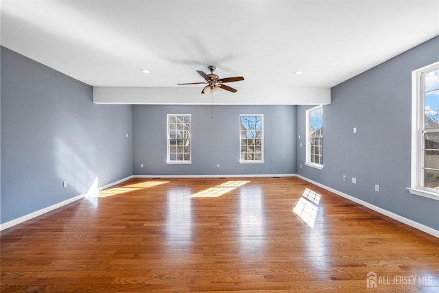 empty room with a healthy amount of sunlight, baseboards, and wood finished floors