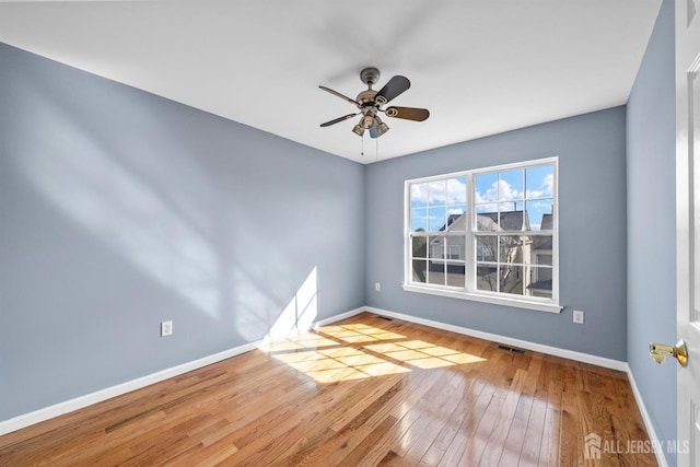 unfurnished room with baseboards, visible vents, and hardwood / wood-style floors