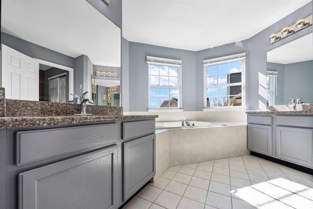 full bathroom with two vanities, a garden tub, a sink, and tile patterned floors