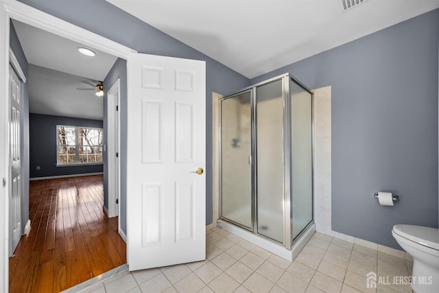 full bath featuring ceiling fan, tile patterned flooring, toilet, baseboards, and a shower stall