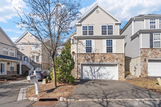 traditional-style home featuring aphalt driveway, stone siding, and a garage