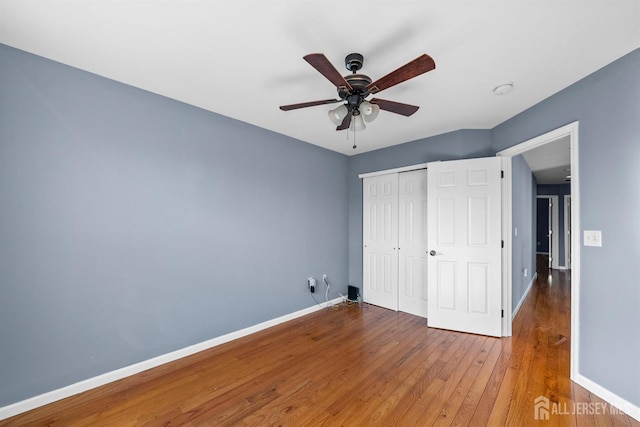 unfurnished bedroom featuring ceiling fan, hardwood / wood-style floors, a closet, and baseboards