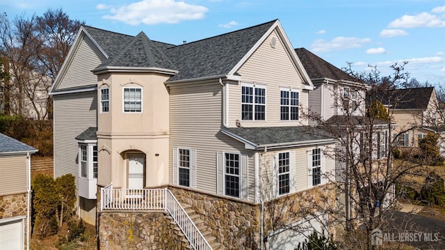 view of front of home with stone siding and roof with shingles