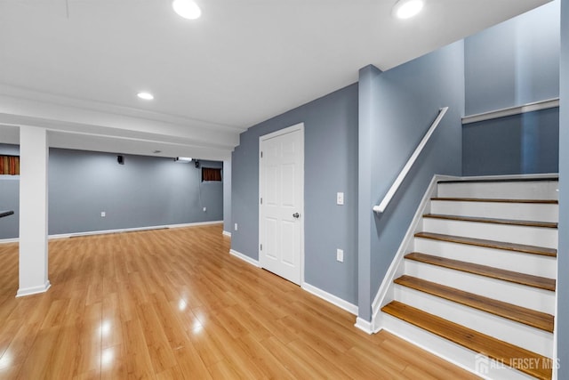 finished basement featuring light wood-style flooring, stairs, baseboards, and recessed lighting