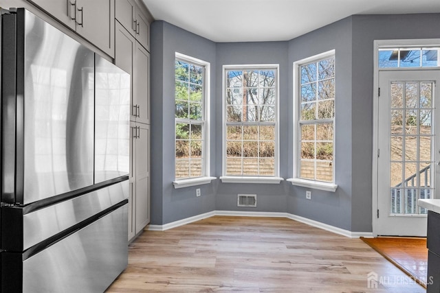 interior space with light wood-type flooring, visible vents, and baseboards