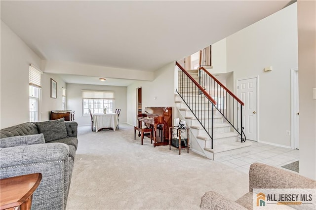 living room featuring baseboards, light carpet, and stairway