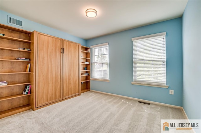 unfurnished bedroom with carpet floors, baseboards, and visible vents