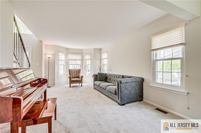 living room featuring visible vents, carpet flooring, and a wealth of natural light