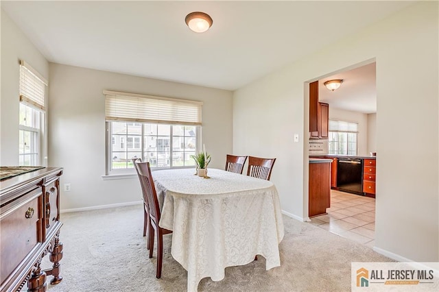 dining area with baseboards and light colored carpet