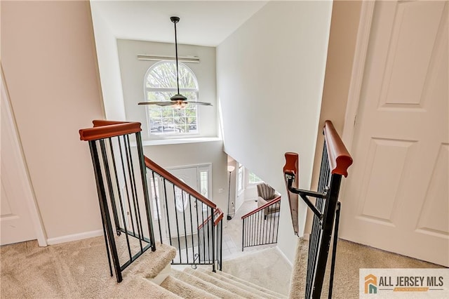 stairs featuring carpet floors, baseboards, and a ceiling fan