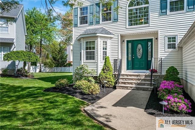 view of exterior entry with a lawn and fence