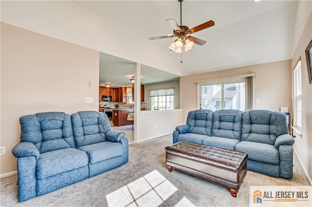living area featuring baseboards, ceiling fan, vaulted ceiling, and light carpet