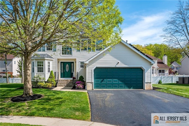 view of front of house featuring a garage, fence, driveway, and a front yard