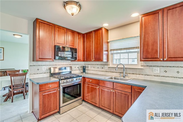 kitchen featuring black microwave, tasteful backsplash, gas stove, light tile patterned floors, and a sink