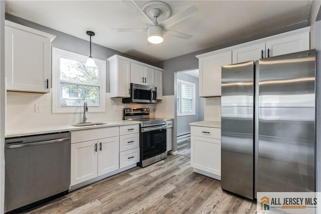 kitchen with a healthy amount of sunlight, a sink, white cabinets, light wood-style floors, and appliances with stainless steel finishes