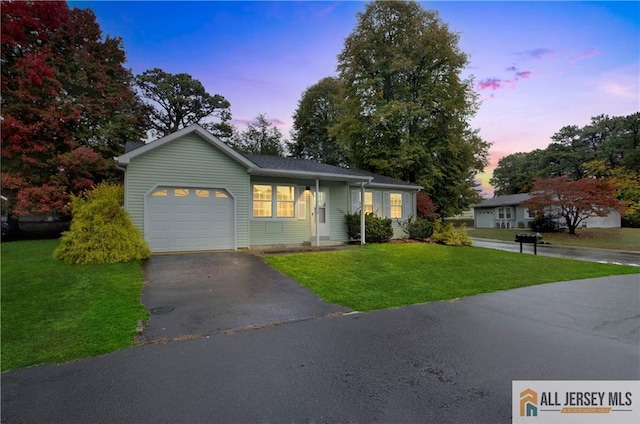 ranch-style house with aphalt driveway, an attached garage, and a lawn