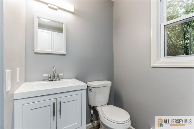 bathroom featuring baseboards, toilet, and vanity