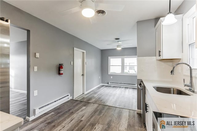 kitchen featuring a baseboard heating unit, baseboard heating, wood finished floors, white cabinets, and a sink