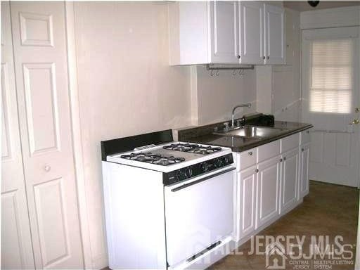 19 Haag St, Sayreville, NJ 08872 - kitchen featuring white gas stove, dark countertops, and white cabinets