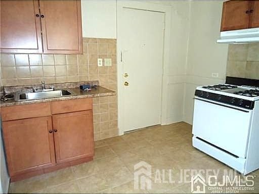 19 Haag St, Sayreville, NJ 08872 - kitchen featuring white range with gas stovetop, under cabinet range hood, decorative backsplash, and light countertops