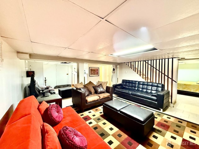 living room featuring stairs and a drop ceiling