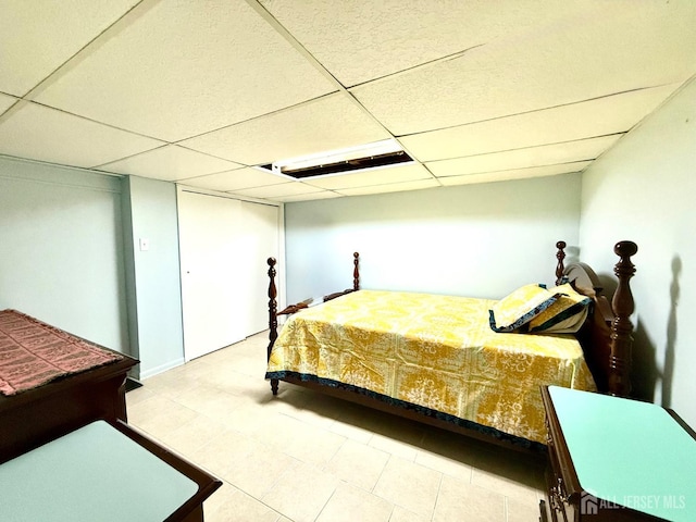 bedroom with a paneled ceiling and tile patterned flooring
