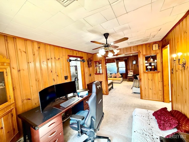 home office featuring visible vents, light colored carpet, wood walls, and a ceiling fan