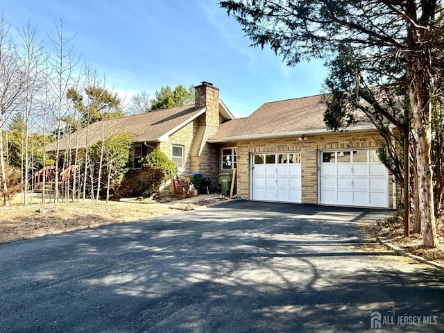 ranch-style house with roof with shingles, an attached garage, driveway, and a chimney