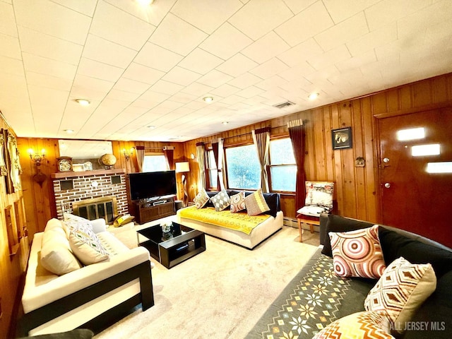 carpeted living area with visible vents, a baseboard heating unit, wood walls, and a fireplace