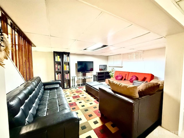 living area with tile patterned floors and a paneled ceiling