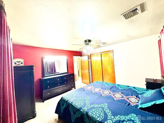 carpeted bedroom featuring a ceiling fan, visible vents, and a closet