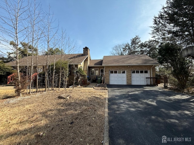 ranch-style house featuring driveway, stone siding, a chimney, a garage, and a shingled roof