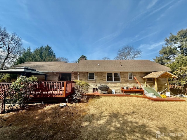 back of property featuring a chimney, a wooden deck, roof with shingles, and a gazebo