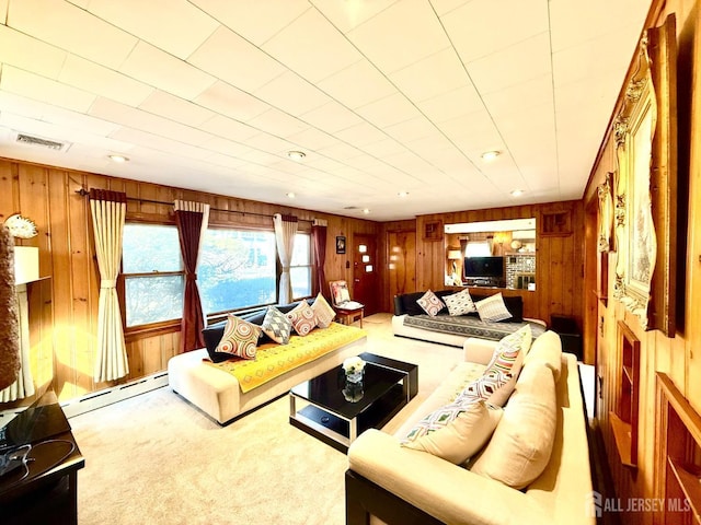 carpeted living room with visible vents, baseboard heating, and wood walls