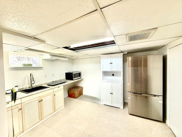 kitchen featuring visible vents, a sink, light countertops, a paneled ceiling, and appliances with stainless steel finishes