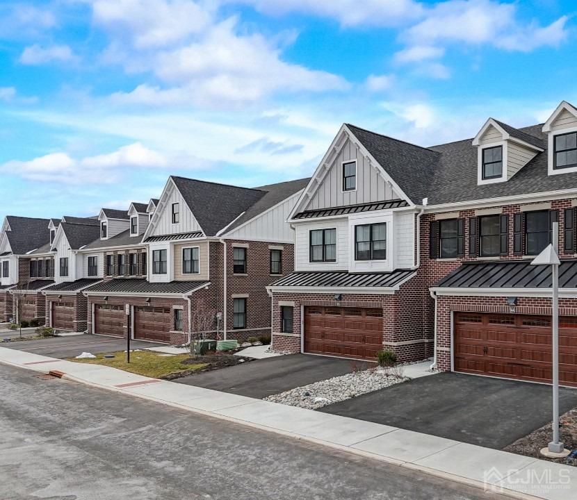 multi unit property with a residential view, brick siding, board and batten siding, and an attached garage