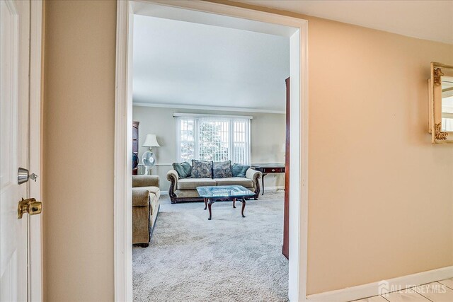hallway with carpet floors, ornamental molding, and baseboards